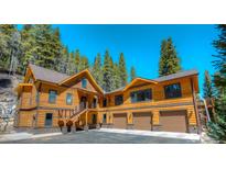 Stunning exterior showcasing the home's wood design, three-car garage, and a beautiful forested surrounding landscape at 6087 Highway 9, Breckenridge, CO 80424