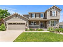 Charming two-story home with stone accents, a covered porch, an attached two-car garage and well-manicured lawn at 7099 Cerney Cir, Castle Pines, CO 80108