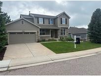 Charming two-story home featuring stone accents, a covered porch, and a well-manicured lawn at 7099 Cerney Cir, Castle Pines, CO 80108
