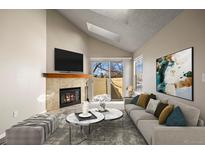 Bright living room featuring a fireplace, skylight, and sliding glass doors to a private outdoor space at 8690 Allison St # H, Arvada, CO 80005