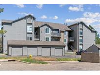 Apartment complex exterior with gray siding, garages, and well-maintained landscaping on a sunny day at 2575 S Syracuse Way # 101, Denver, CO 80231