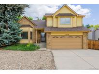 Two-story home featuring a front-facing two-car garage, brick and shingle siding, and lush landscaping at 12319 W Burgundy Ave, Littleton, CO 80127