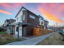 Modern home featuring wood and stucco siding, with a privacy fence and beautiful sunset in the background at 3600 N Pecos St, Denver, CO 80211