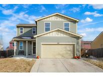 Two-story house with light green exterior, two-car garage, and landscaping at 334 Feather Pl, Lochbuie, CO 80603