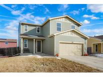 Two-story house with light green exterior, two-car garage, and landscaping at 334 Feather Pl, Lochbuie, CO 80603