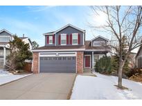 Two-story house with gray siding, red brick accents, and a two-car garage at 3836 Garnet Way, Highlands Ranch, CO 80126