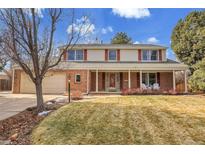 Charming two-story home with brick facade, neutral siding, red shutters, well-maintained lawn, and attached two-car garage at 9720 E Pinewood Ave, Englewood, CO 80111