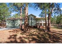 Charming green two-story home with brick foundation and a beautiful wooded front yard at 4185 Red Rock Dr, Larkspur, CO 80118