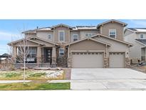 Beautiful home exterior with a three car garage, stone accents, and inviting covered front porch at 6614 S Vandriver Way, Aurora, CO 80016