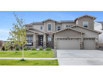 Stunning two-story home featuring a three-car garage, stone accents, covered porch and well-manicured lawn at 6614 S Vandriver Way, Aurora, CO 80016
