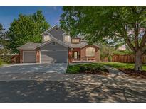 Charming two-story home featuring a brick and gray exterior, well-manicured lawn, and inviting front porch at 10345 Lions Heart, Lone Tree, CO 80124