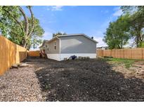 The backyard shows the home's grey siding and the gravel area at 811 Plum N Ave, Lochbuie, CO 80603