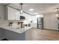 Bright kitchen features modern, stainless steel appliances and quartz countertops with a decorative pendant light at 625 S Alton Way # 3A, Denver, CO 80247