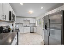 Bright kitchen featuring stainless steel appliances, white cabinets, and a modern tiled backsplash at 3117 Victor St, Aurora, CO 80011