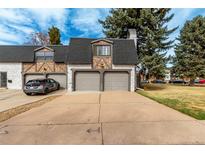 Charming townhome featuring a two-car garage, brick accents, and a well-maintained driveway in a residential neighborhood at 5865 E Ithaca Pl, Denver, CO 80237