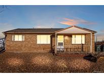 Charming brick home featuring a cozy front porch, well-lit windows, and low-maintenance landscape design at 11624 Claude Ct, Northglenn, CO 80233