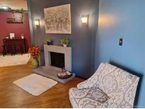 Inviting living room showcases a brick fireplace, hardwood floors, and a comfortable accent chair at 3550 S Harlan St # 313, Denver, CO 80235