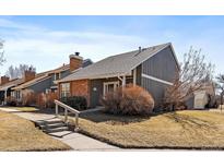 Charming two-story home with brick accents, gray siding, and well-maintained landscaping on a sunny day at 8699 Garrison Ct, Arvada, CO 80005