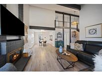Bright living room with a modern fireplace and an open floor plan flows into the dining area and kitchen at 8699 Garrison Ct, Arvada, CO 80005