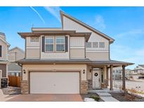 Charming two-story home featuring a front-facing garage, a welcoming porch, and modern architectural details at 10052 Zeno St, Commerce City, CO 80022