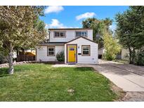 Charming home with a well-manicured lawn and a bright yellow front door at 5570 Otis Ct, Arvada, CO 80002