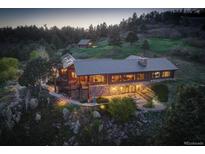 Stunning log home exterior featuring a stone foundation, metal roof, and picturesque hillside setting at 51 West Ranch Trl, Morrison, CO 80465