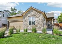 Charming home with a stone facade, well-manicured lawn, and an attached two-car garage at 19677 E Vassar Dr, Aurora, CO 80013