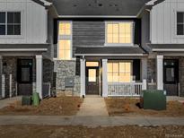 Charming townhome showcasing a stone facade, gray wood siding, and a welcoming front porch at 6581 N Malaya St, Aurora, CO 80019