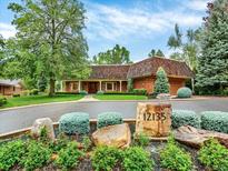 Well-manicured exterior elevation featuring a brick facade, mature trees, and manicured lawn at 12135 W Applewood Knolls Dr, Lakewood, CO 80215