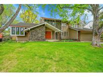 Inviting exterior showcasing a manicured lawn, stone accents, and a striking orange front door at 4012 S Newport Way, Denver, CO 80237