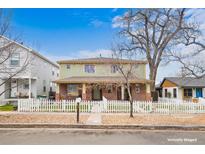 Charming two-story home featuring a brick foundation and a welcoming front porch, surrounded by a white picket fence at 109 Cantril St, Castle Rock, CO 80104
