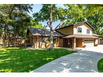 Charming brick two-story home with a well-manicured lawn and a long concrete driveway on a sunny day at 6740 S Windermere St, Littleton, CO 80120