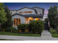 Charming two-story home with manicured landscaping, sidewalk, and inviting entrance with illuminated bushes at 1882 W 67Th Ave, Denver, CO 80221