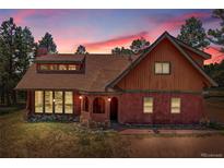 Charming home with unique architecture and a beautiful sunset backdrop, surrounded by mature trees at 26526 Gray Buck Trl, Conifer, CO 80433