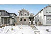 Charming gray two-story home with a covered porch and snowy front yard in a neighborhood setting at 7376 Watercress Dr, Littleton, CO 80125