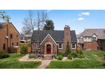 Charming brick home with a red front door, chimney, and well-maintained landscaping at 6023 E 6Th Avenue Pkwy, Denver, CO 80220