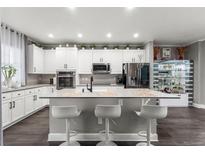 Well-lit kitchen featuring a center island with barstool seating and modern appliances at 3818 S Dallas St, Aurora, CO 80014