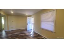 Bright living room featuring updated flooring and natural light from a window and glass door at 1940 Quince St, Denver, CO 80220