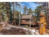 Charming wood home featuring a spacious deck and a unique owl carving nestled in a serene wooded setting at 20606 Yoke Trl, Morrison, CO 80465