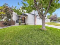 Charming two-story home featuring a manicured lawn and a welcoming front porch with a beautiful tree at 9867 Mulberry Way, Highlands Ranch, CO 80129