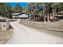 Charming home with a split rail fence, a long driveway, and a two-car garage at 24949 N Mountain Park Dr, Evergreen, CO 80439