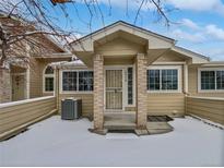 Tan exterior of house with snow covered front yard and entryway at 7770 W 90Th Dr, Broomfield, CO 80021