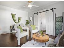 Inviting living room features white armchairs, modern sliding barn doors, and wood floors at 65 N Logan St # B4, Denver, CO 80203
