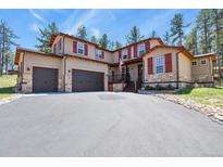 Charming two-story home with a three-car garage, stone accents, and red shutters on a spacious lot at 7947 Monarch Rd, Larkspur, CO 80118