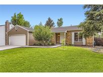 Charming ranch-style home with a lush green lawn, mature trees, and a two-car garage at 17404 E Prentice Cir, Centennial, CO 80015