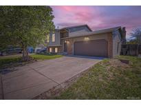 Two-story home featuring a two-car garage, brick accents, and a well-maintained front yard under a dramatic sunset sky at 8438 Prairie Clover Way, Parker, CO 80134