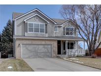 Charming two-story home with a well-manicured lawn, attached garage, and inviting front porch at 14656 W Vassar Dr, Lakewood, CO 80228