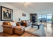 Bright living room featuring a fireplace, comfortable seating, and city views from the large windows at 1777 Larimer St # 1203, Denver, CO 80202