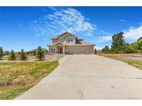 Inviting two-story home featuring a three car garage and landscaped front yard at 497 Valley Way, Bennett, CO 80102