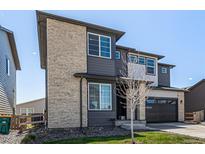 Modern two-story home with stone accents and a paved driveway and a two-car garage with a well kept lawn at 23652 E 40Th Ave, Aurora, CO 80019